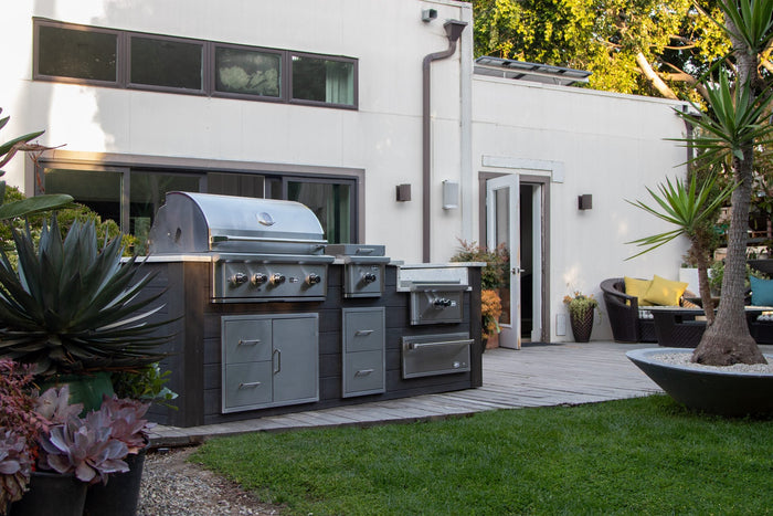 Wildfire Ranch Pro stainless steel grill with matching access doors and drawers built into a modern backyard outdoor kitchen