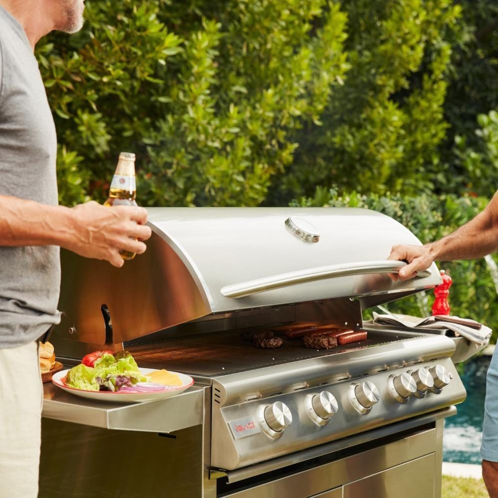 People preparing food beside a Blaze Professional LUX freestanding grill outdoors