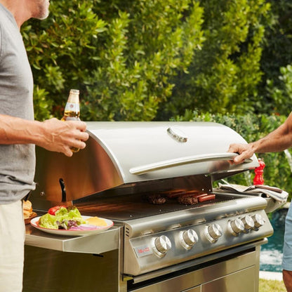 People preparing food beside a Blaze Professional LUX freestanding grill outdoors