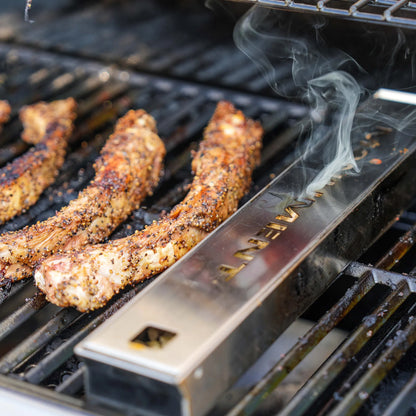 Monument Grills smoker box on a grill grate next to ribs