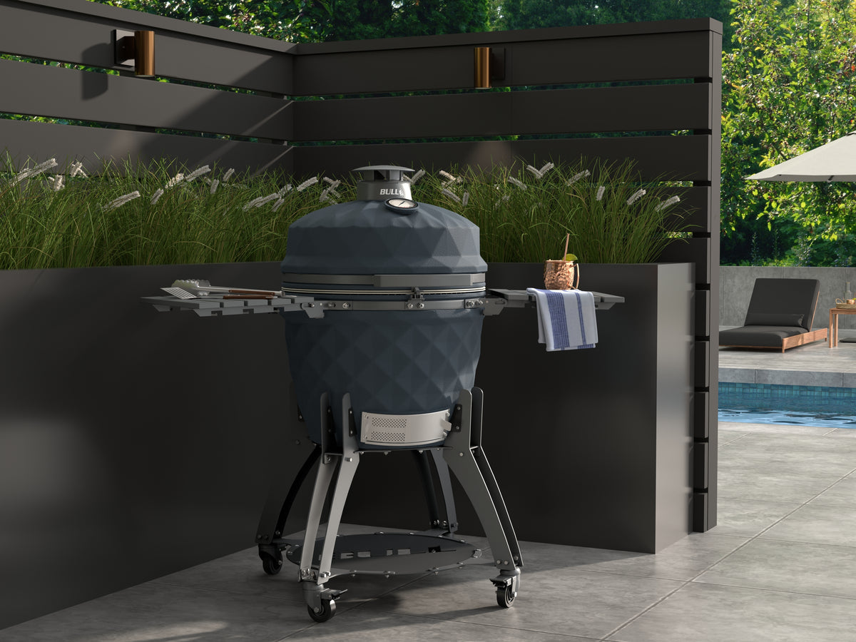 Bull Blackhorn 24-inch ceramic kamado grill on cart on a poolside patio