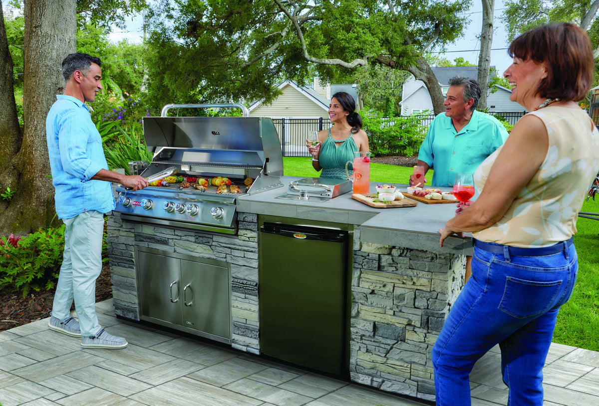 Bull Brahma grill in a stone outdoor kitchen island with friends gathered