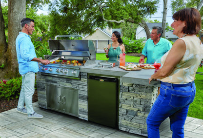 Bull Brahma grill in a stone outdoor kitchen island with friends gathered